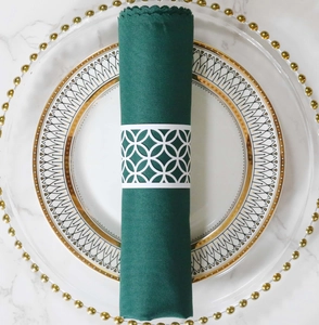 Detalle del servilletero blanco cortado con láser sobre una servilleta de tela verde oscuro