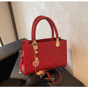 Macro shot of red quilted faux leather tote with woven handles and bridal charm