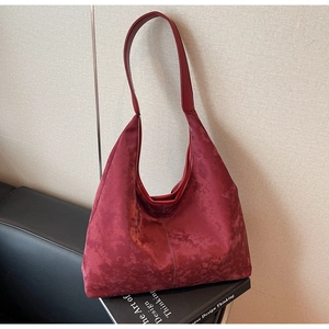 Macro shot of burgundy hobo bag in soft suede material with elegant leather shoulder strap