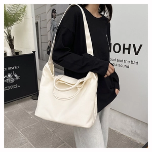 Off-white canvas tote bag with shoulder straps shown in an urban street setting