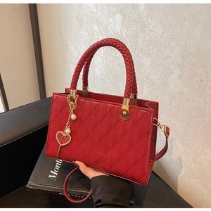 Detailed view of red quilted leather tote with heart charm and gold hardware accents
