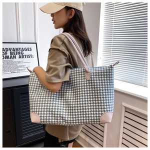 Détail du grand sac de voyage pied-de-poule bleu avec anses en cuir rose et fermeture éclair