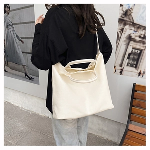 Detail view of the large off-white canvas tote bag showing the magnetic buckle and strap