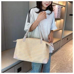 Détail du grand sac de voyage à motif pied-de-poule avec poignées en cuir sur modèle