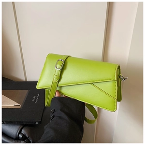 Detail of bright green leather crossbody bag with asymmetric flap and silver buckle