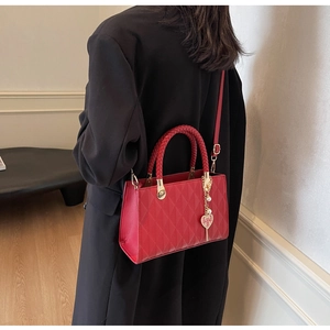 Detail of red bridal tote bag with lattice pattern and heart-shaped wedding charm