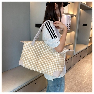 Vue latérale d'un grand sac de voyage à motif pied-de-poule porté par un mannequin
