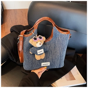 Detail of denim and leather bucket bag with a cute teddy bear charm and strap