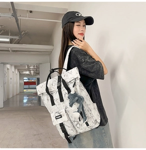 Side view of large marble print backpack with buckle straps and plush frog charm accessory