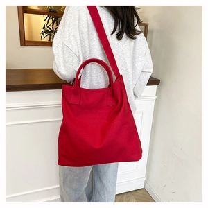 Detail view of large red canvas tote bag shown on a model for scale and fit