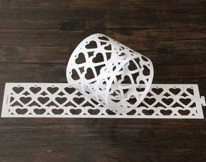 Detailed laser-cut white heart pattern paper napkin ring on dark wooden background