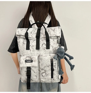 Detail showing the white marble texture of the backpack with a grey plush doll charm