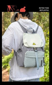 Outdoor backpack detail showing three-color patchwork fabric and smile face logo