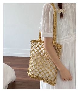 Detail of gold metallic hollow woven tote bag with a white drawstring inner pouch