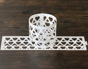 Macro shot of white laser-cut paper napkin ring with intricate hollow heart patterns