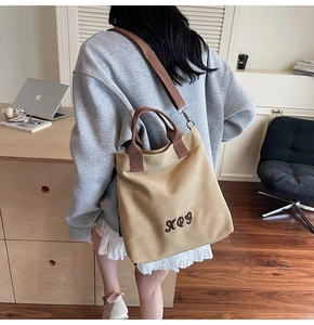 Detail of khaki canvas tote bag with brown woven handles and RO9 letter embroidery