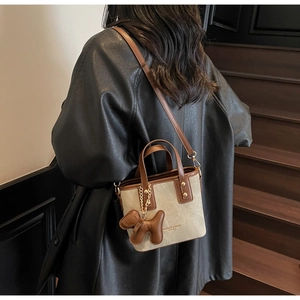 Détail du sac seau rétro en tissu beige et cuir marron avec un pendentif chiot mignon