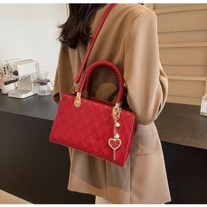 Detail of red quilted tote bag with woven handles and golden Double Happiness charm