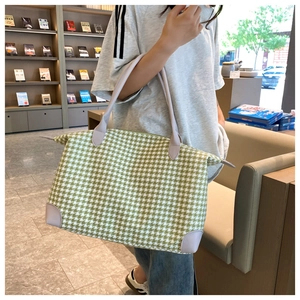 Sac fourre-tout en pied-de-poule vert avec finitions en cuir violet dans une librairie