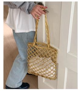 Detailed shot of gold woven tote bag with hollow mesh pattern and white inner pouch