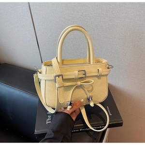 Detail of light yellow bucket bag with bow tie, star charm and lychee texture finish