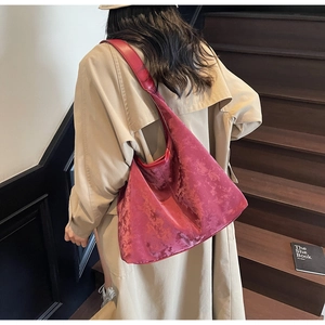 Detail of the burgundy tote bag with wide strap on model in elegant trench coat