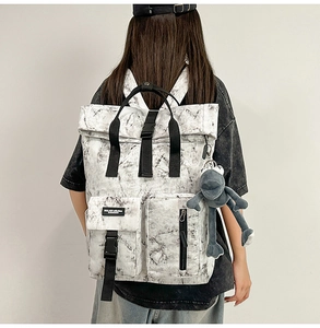Detail view of large marble print backpack with buckle pockets and a plush frog charm