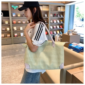 Détail du sac de voyage pied-de-poule vert avec coins et poignées en cuir renforcé
