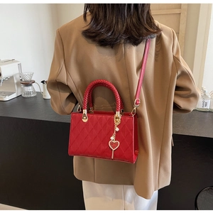 Detail of red quilted tote with woven handle and gold heart charm for bridal use