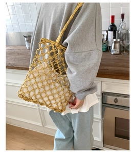 Detail of gold mesh woven tote bag with a white drawstring inner pouch and strap