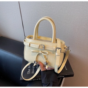 Detail of light yellow bucket bag featuring a delicate bow and star charm on a book