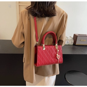 Detail of red quilted bridal tote featuring woven handles and heart pendant with Double Happiness
