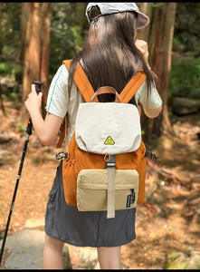 Outdoor backpack detail showing color-block nylon fabric and smiley face emblem