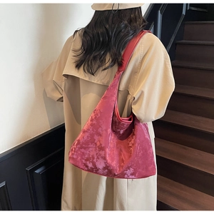 Detail of rose red velvet tote bag showing soft texture and glossy finish on model