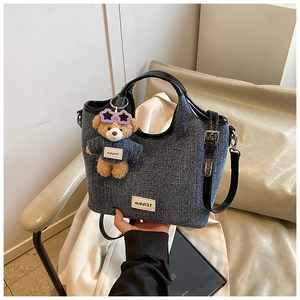 Detail of blue denim bucket bag with leather handles and cute bear charm accessory