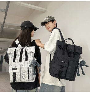 Detail of roll-top backpack featuring marble pattern and plush frog charm accessory