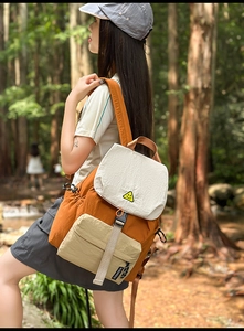 Detail of color-block nylon backpack featuring a smiley face badge and buckle closure