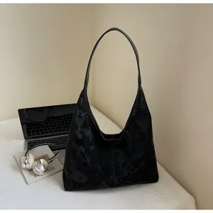 Detail of a black large hobo shoulder bag with a soft velvet texture in a cozy setting