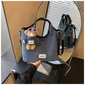 Detail of vintage denim tote with leather handles and MDDJ37 bear charm accessory