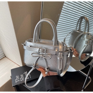 Detailed side view of silver metallic pleated handbag with star charm bow and shoulder strap