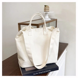 Detail view of a white canvas tote bag with dual straps in a bright lifestyle setting