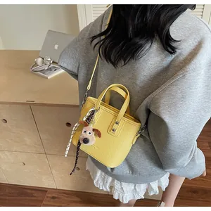 Detail of yellow lychee texture mini bucket bag with plush dog charm and striped scarf