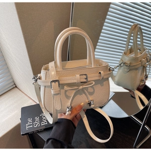 Detail of cream bucket bag with embossed leather, metal buckle and star charms