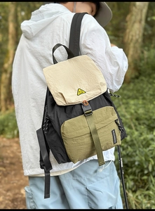 Detail of multi-color nylon backpack featuring buckle closure and side brand tag in nature