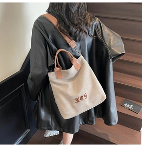 Detail of minimalist beige canvas tote bag with brown embroidered script and adjustable strap