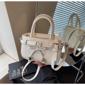 Detail of cream white pleated bucket bag with bow decoration and metal star charms