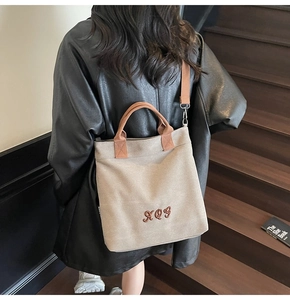Detail of light brown canvas tote with XQY embroidery and detachable shoulder strap