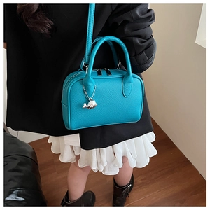 Turquoise pebble leather bowling handbag with a whale charm shown on a child model