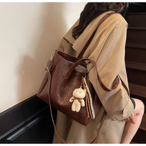 Detail of dark brown woven tote bag showing fine texture and plush bear charm