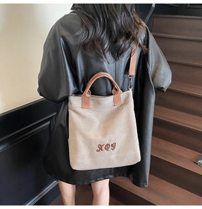 Detail of canvas tote bag with brown leather handles and adjustable shoulder strap